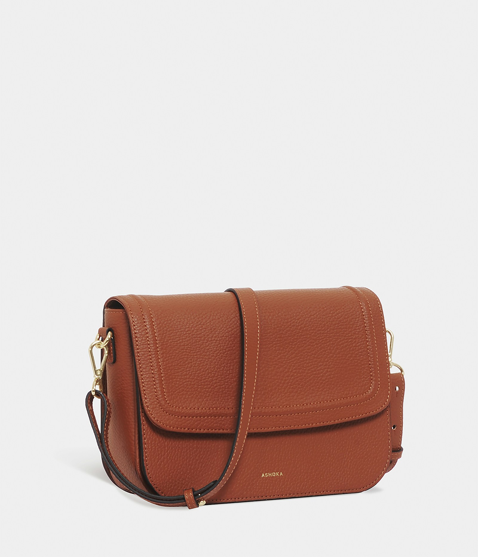 The Aria shoulder bag in tan full-grain leather with a flap front and brass hardware.